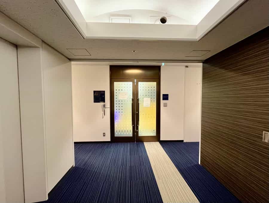 【左手にある共用扉の前で、予約完了メールに記載のAkerunのURLを開き「開ける」ボタンを押すと開錠されます】